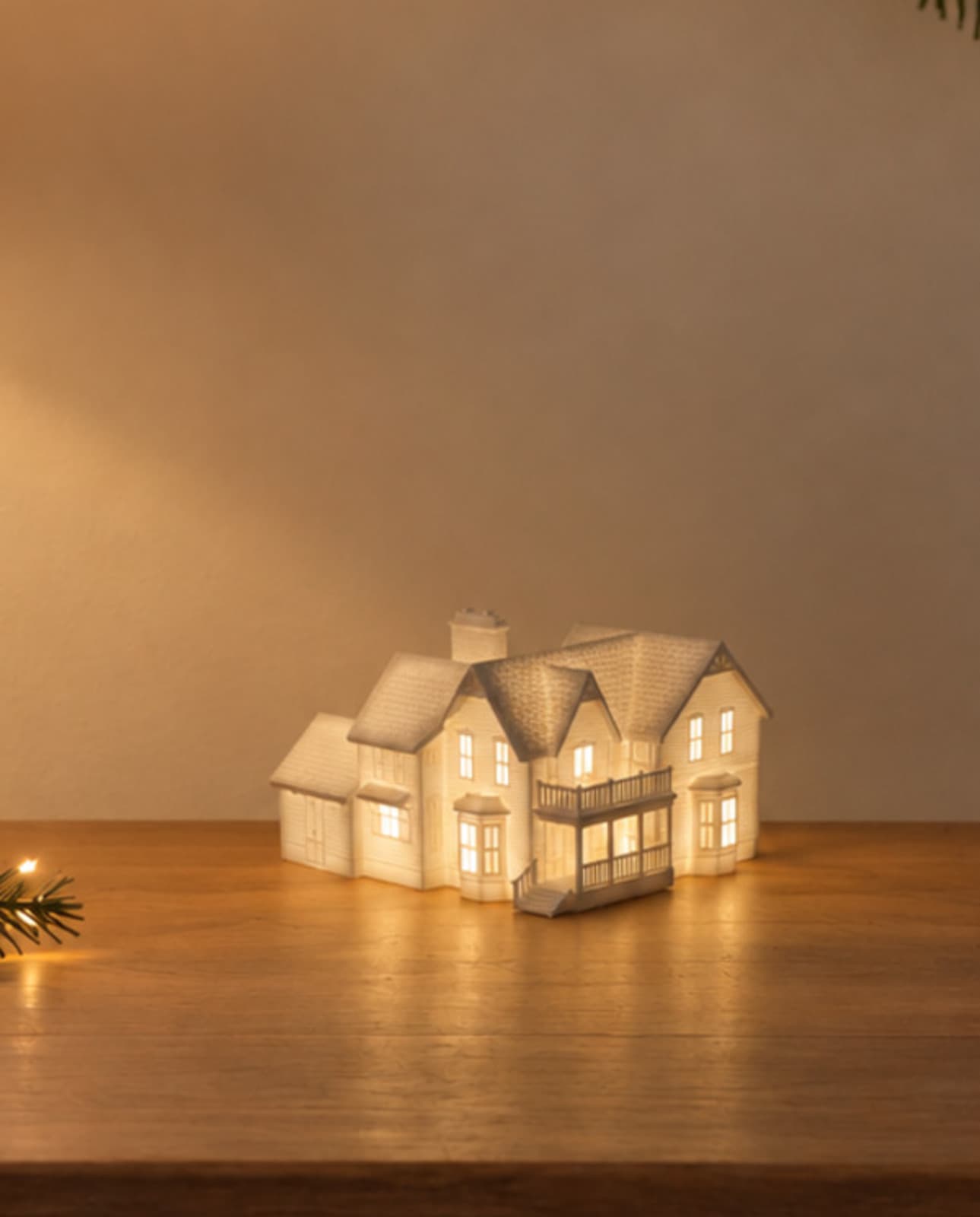 One white house sculpture with a side garage glowing from inside on a wood console table