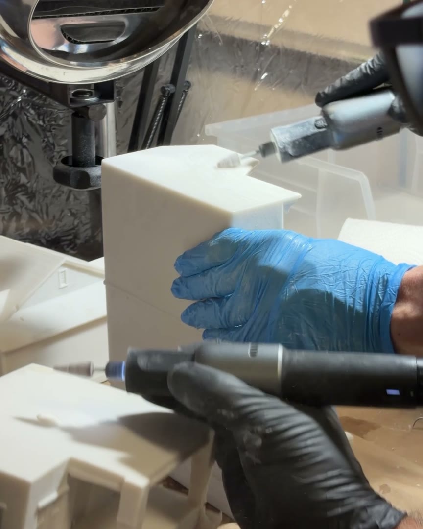 Gloved hands finishing a white printed piece with a rotary tool in our workshop