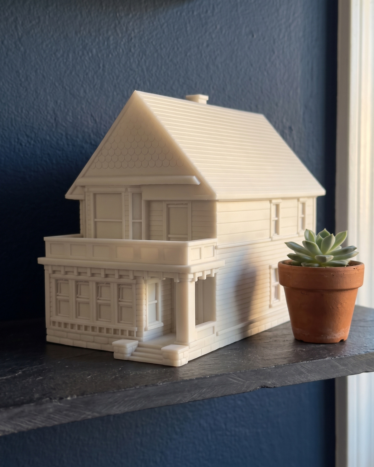 A finished white Victorian house piece with a front porch on a slate shelf against a navy wall, in a generated picture