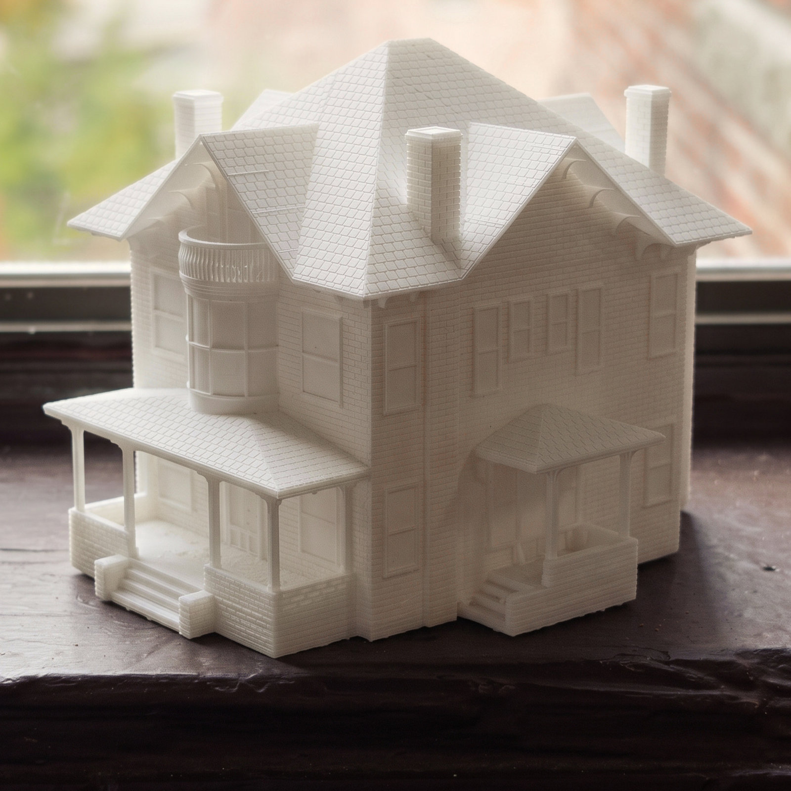 A finished shingle Victorian house keepsake with a wraparound porch at a city window