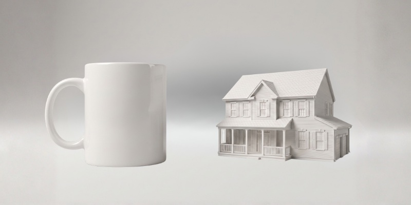 The small matte white house keepsake next to a coffee mug for scale